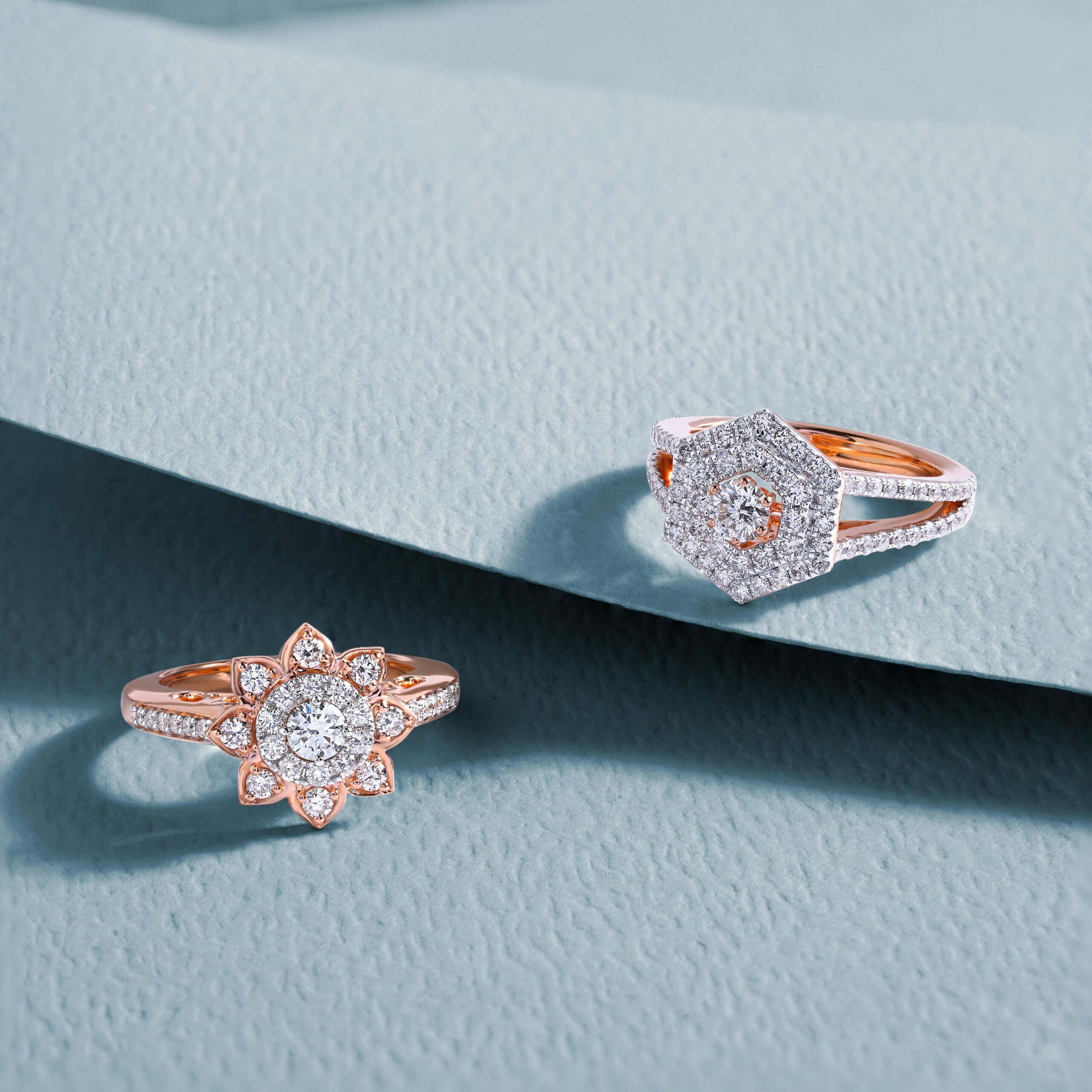 Luxurious diamond rings displayed on a textured blue background, showcasing elegance and style.